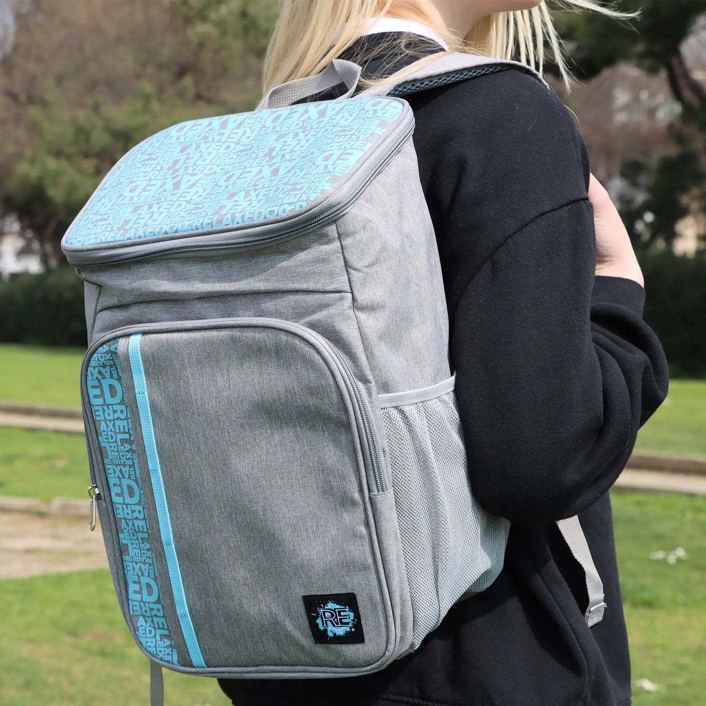 Person wearing a gray and blue backpack with text design outdoors.