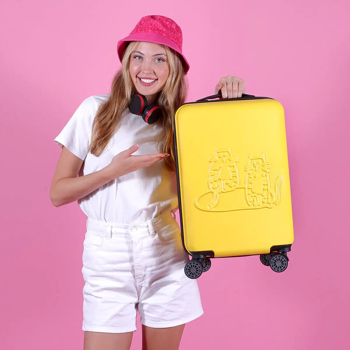 Woman holding a yellow suitcase with a pink background