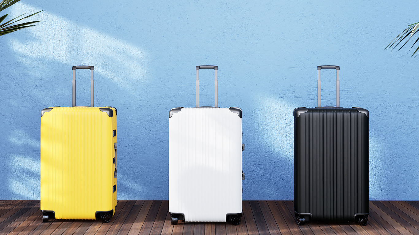 Three suitcases of different colors (yellow, white, black) on a wooden floor with a blue wall background.
