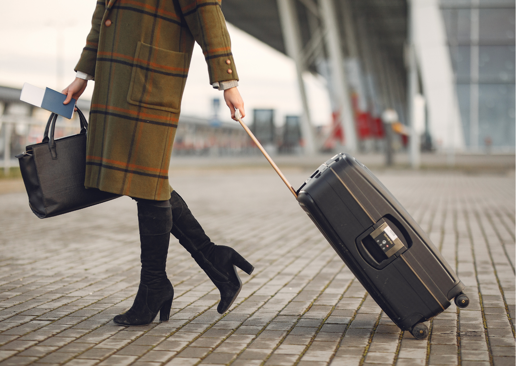 Person walking with a suitcase and handbag in an urban setting